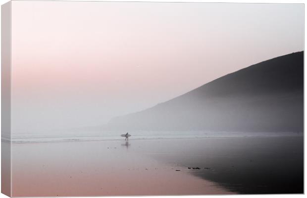 A surfer walking along a misty beach Canvas Print by David Wall