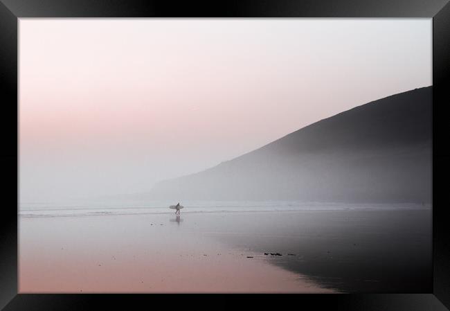 A surfer walking along a misty beach Framed Print by David Wall
