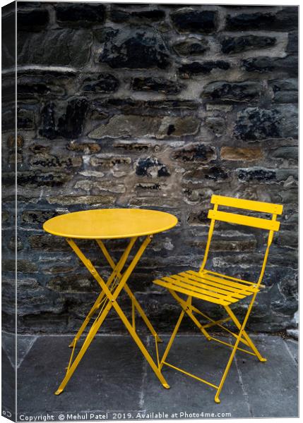 Yellow chair and table by stone wall  Canvas Print by Mehul Patel