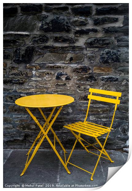 Yellow chair and table by stone wall  Print by Mehul Patel
