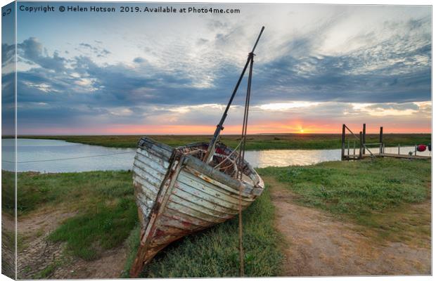 Sunrise over abandoned fishing boat on the shore a Canvas Print by Helen Hotson