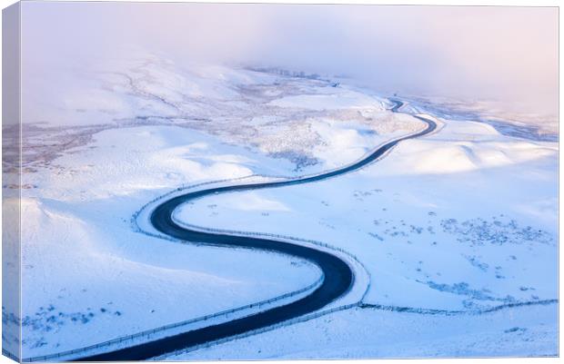Bendy road through the snow Canvas Print by Andrew Kearton