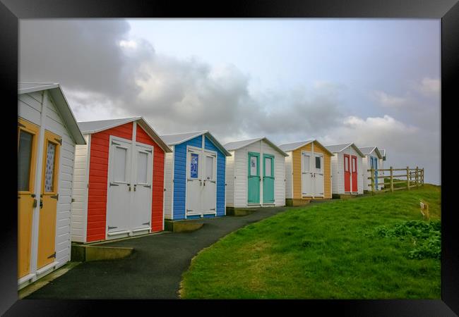 Curving Beach Huts Framed Print by Dave Bell