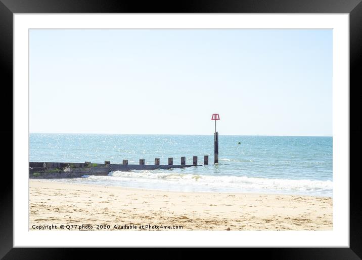Dock pilings on a sandy beach, blue ocean and yell Framed Mounted Print by Q77 photo