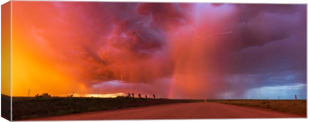 Sunset thunderstorm with rainbow and lightning. Canvas Print by John Finney
