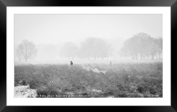 Solitary figure wanders through snow storm Framed Mounted Print by Chris Rabe