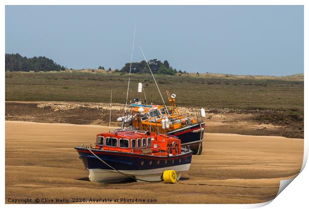 Lifeboats on the mud flats at Wells-Next-Sea Print by Clive Wells