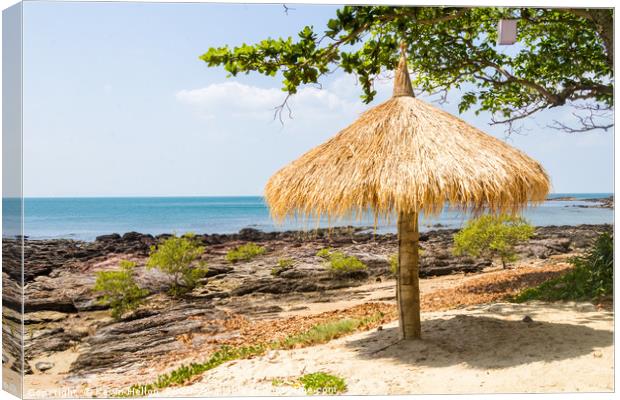 Straw parasol on beach with rocks, Kho Lanta, Thai Canvas Print by Kevin Hellon