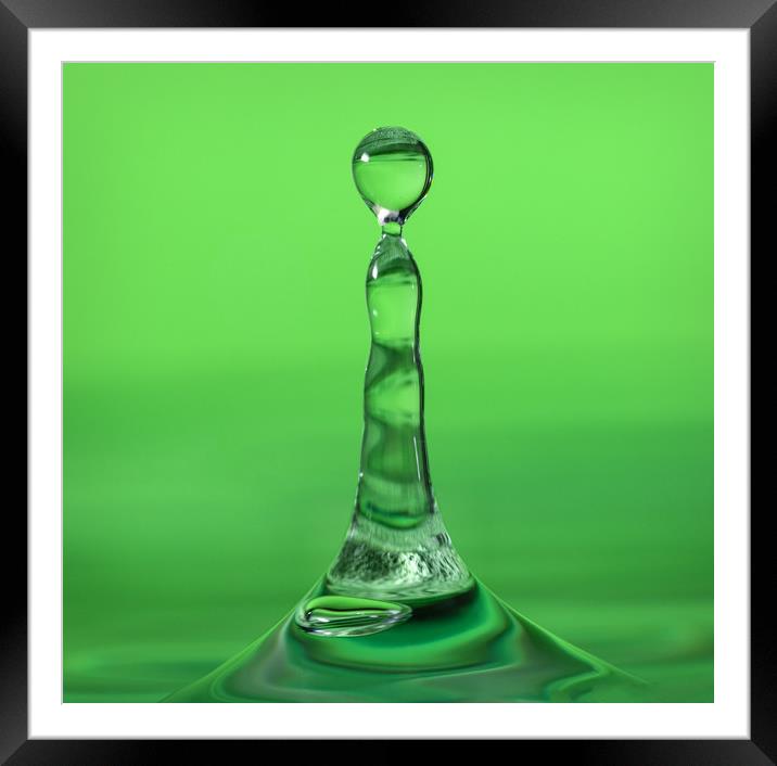 Water droplet landing in water on a green backgrou Framed Mounted Print by Dave Collins