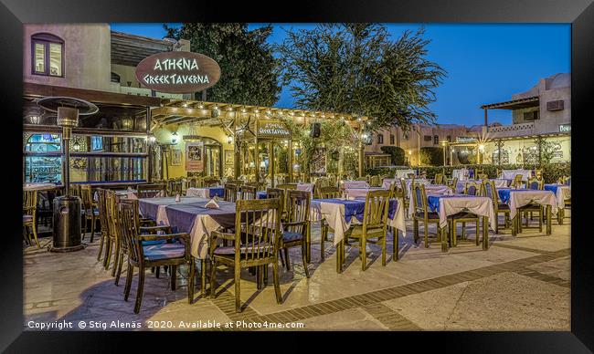 illuminated greek taverna with tables and chairs i Framed Print by Stig Alenäs