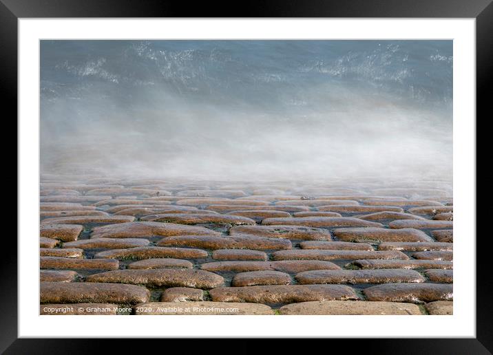 Wave splashes on cobbles Framed Mounted Print by Graham Moore