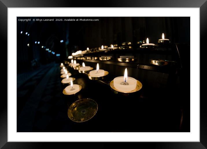 Prayer candles shine bright in a dark cathedral Framed Mounted Print by Rhys Leonard