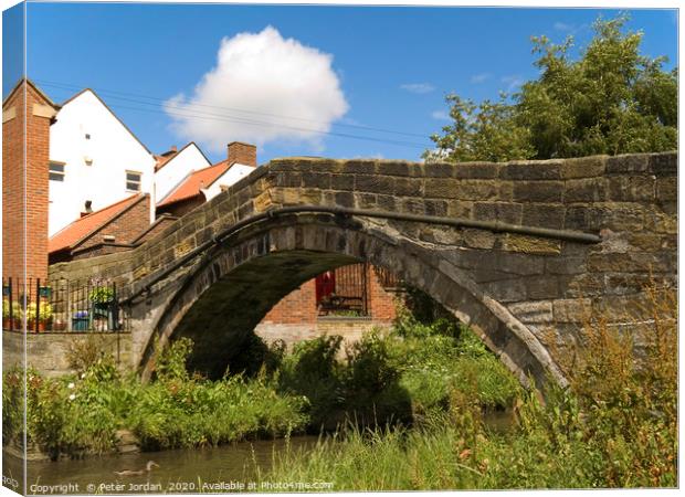 An old pack horse bridge joining the High Street t Canvas Print by Peter Jordan