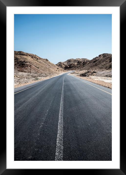 An empty tarmac road going thru arid mountains in  Framed Mounted Print by David GABIS