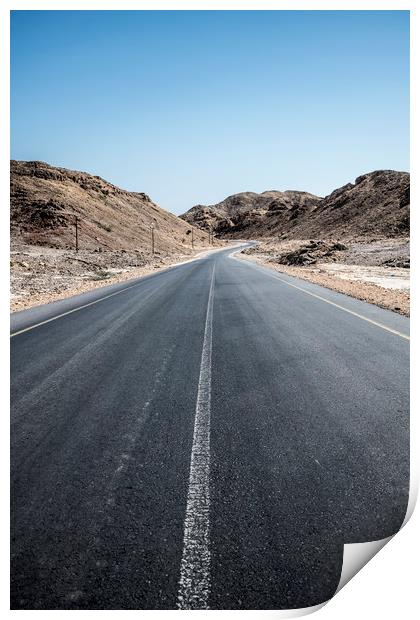 An empty tarmac road going thru arid mountains in  Print by David GABIS