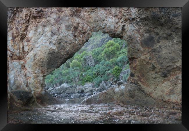 Frame view through a hole in a rock at a coast Framed Print by Hanif Setiawan