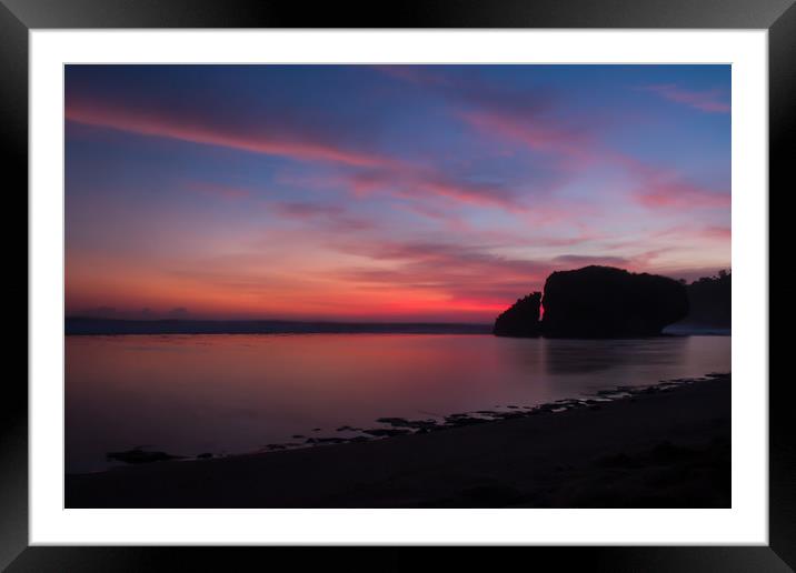 Silhouetted reflecting rock at sunset on sandbeach Framed Mounted Print by Hanif Setiawan