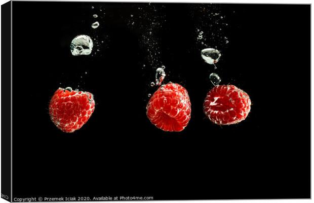 Raspberries splashing into clear water isolated on black background. Canvas Print by Przemek Iciak