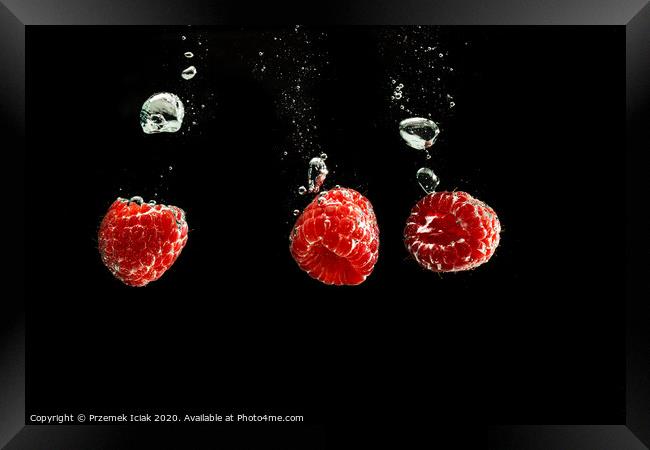 Raspberries splashing into clear water isolated on black background. Framed Print by Przemek Iciak