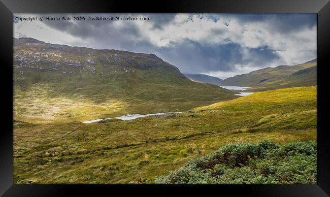 A lush green hillside with three lochs in the back Framed Print by Marcia Reay
