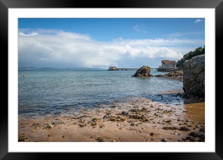 A rocky beach next to a body of water Framed Mounted Print by Bryn Morgan