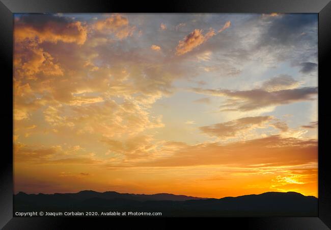 Beautiful sunset with the sun of orange tones behind the mountains and deep blue sky Framed Print by Joaquin Corbalan