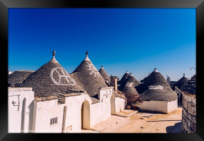 Alberobello, Italy - March 9, 2019:  Roofs with symbols in the trulli, in the famous Italian city of Alberobello. Framed Print by Joaquin Corbalan
