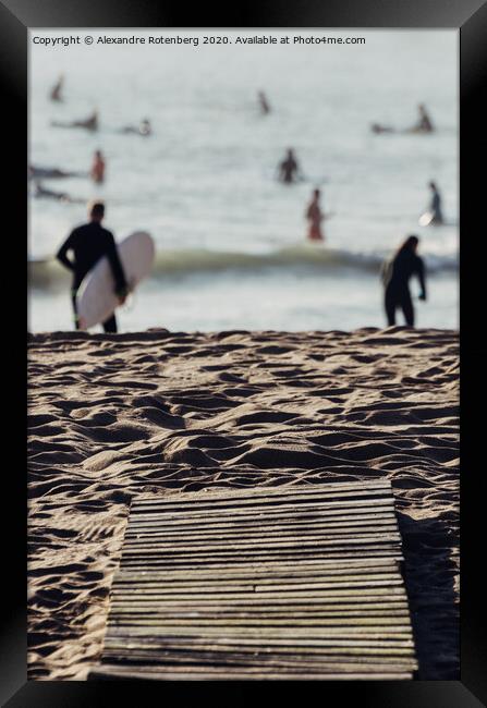 Wooden boards on beach leading to surfers on water Framed Print by Alexandre Rotenberg