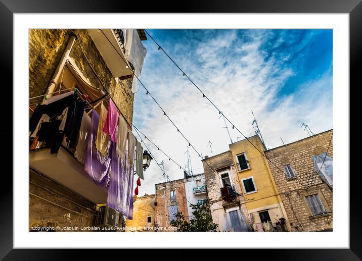 Colorful clothes tended to dry on the balconies of the old houses of an Italian city in the Mediterranean. Framed Mounted Print by Joaquin Corbalan