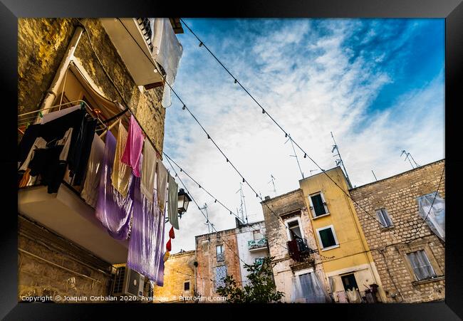 Colorful clothes tended to dry on the balconies of the old houses of an Italian city in the Mediterranean. Framed Print by Joaquin Corbalan