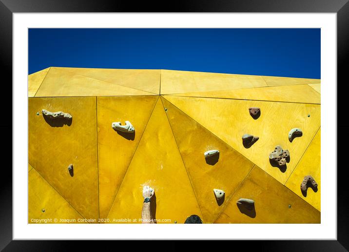 Young man grabs to try climbing on an outdoor climbing wall in a park in Valencia. Framed Mounted Print by Joaquin Corbalan