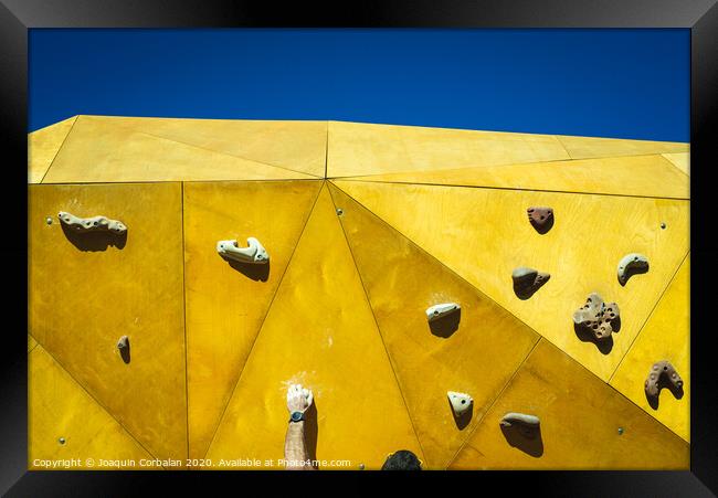 Young man grabs to try climbing on an outdoor climbing wall in a park in Valencia. Framed Print by Joaquin Corbalan