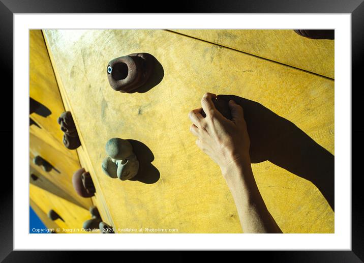 Hand of a person trying to climb the fixie of a climbing wall Framed Mounted Print by Joaquin Corbalan