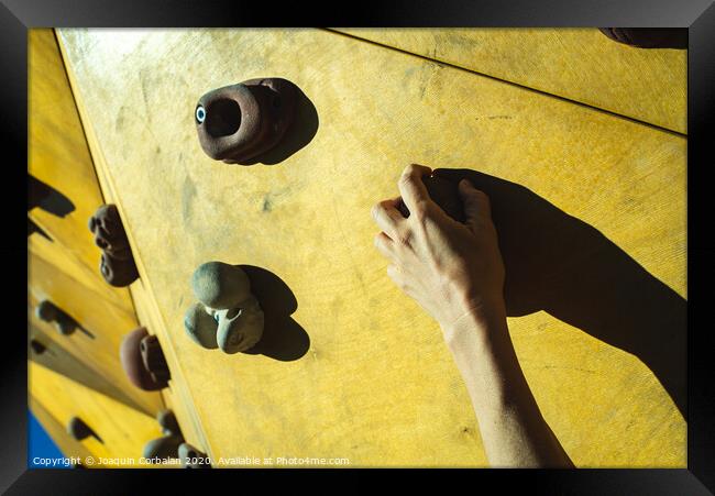 Hand of a person trying to climb the fixie of a climbing wall Framed Print by Joaquin Corbalan
