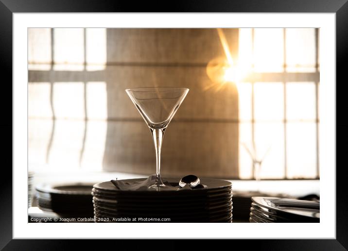 Empty glass cup with sun flares background in a restaurant. Framed Mounted Print by Joaquin Corbalan