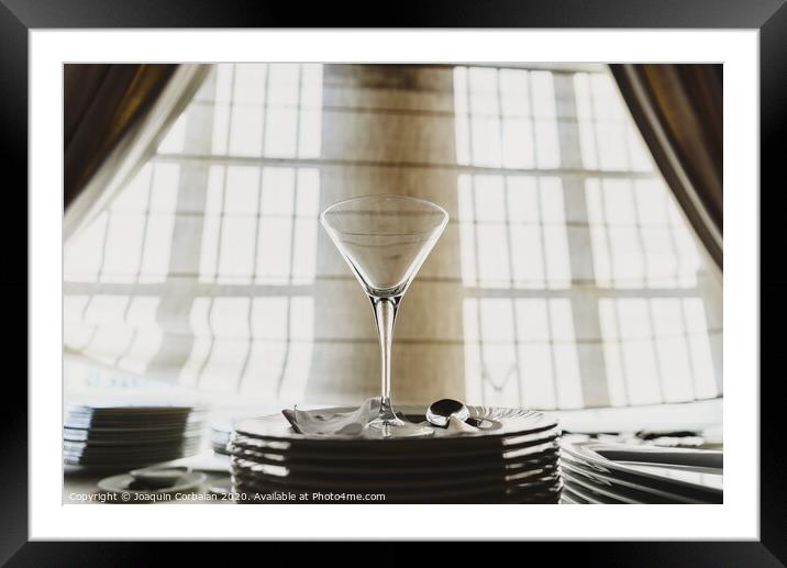 Empty glass cup with sun flares background in a restaurant. Framed Mounted Print by Joaquin Corbalan