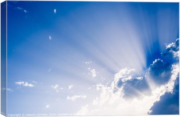 Sunbeams rising from a large cloud in intense blue sky on a summer afternoon Canvas Print by Joaquin Corbalan