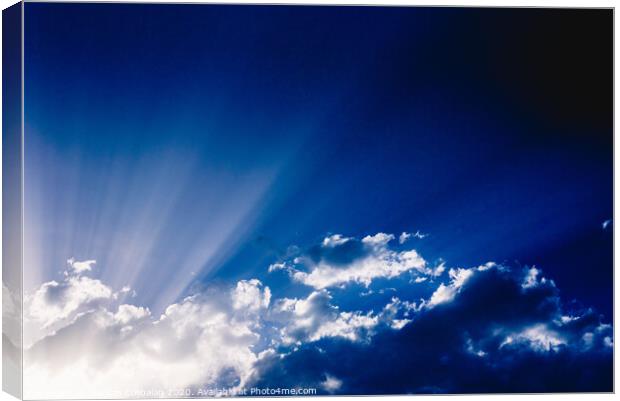 Sunbeams rising from a large cloud in intense blue sky on a summer afternoon Canvas Print by Joaquin Corbalan