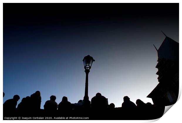  A crowd of tourists rests at dusk on a bridge, silhouetted images backlight against a streetlight. Print by Joaquin Corbalan