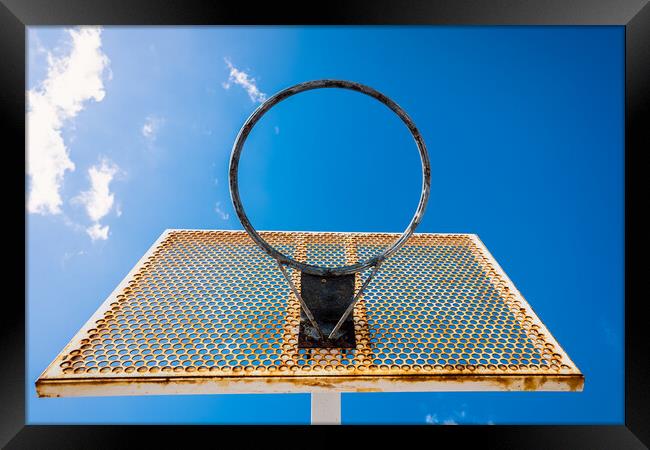 An old basketball basket outside a street with blue sky, copy space for text. Framed Print by Joaquin Corbalan