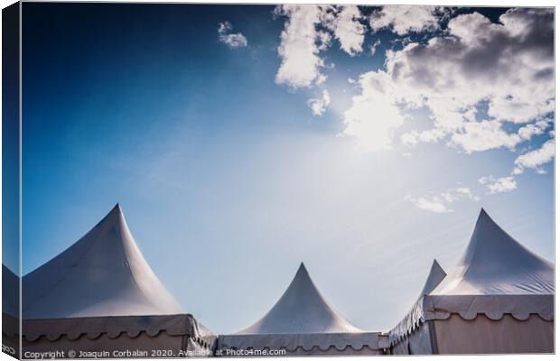 Peaks of three pyramidal white tents and blue sky background with space for advertisers text. Canvas Print by Joaquin Corbalan