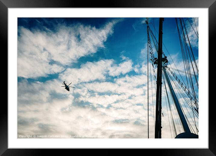  Rescue helicopter flying over a sailboat, seen from the sea. Framed Mounted Print by Joaquin Corbalan