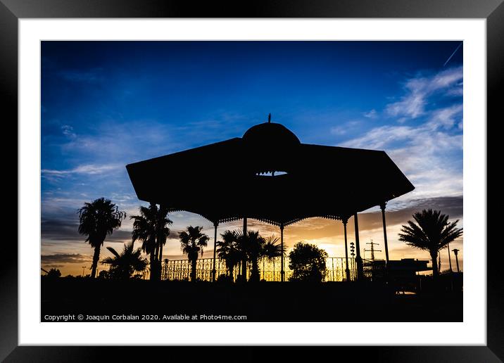Silhouette of a pergola at sunset on a cloudy afternoon in the port of the Marina Real of Valencia, Spain. Framed Mounted Print by Joaquin Corbalan