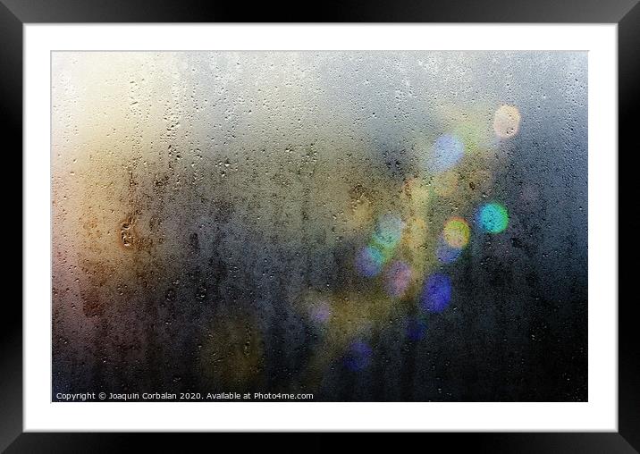 Beams of lights through a wet glass on a dark night, background of cold drops of water. Framed Mounted Print by Joaquin Corbalan