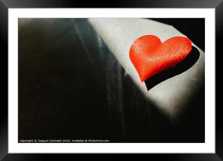 Red hearts isolated dark background illuminated by a ray of sun to use in the background, with a lot of empty space copy space. Framed Mounted Print by Joaquin Corbalan