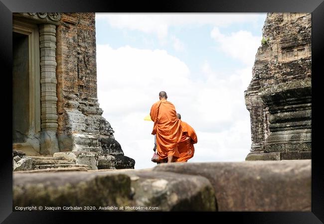 Tibetan monks in orange robes visiting remote Cambodian temples to meditate. Framed Print by Joaquin Corbalan