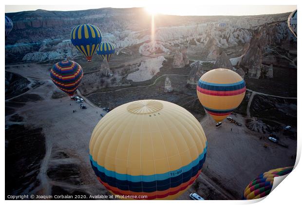 Hot air balloons for tourists flying over rock formations at sunrise in the valley of Cappadocia. Print by Joaquin Corbalan