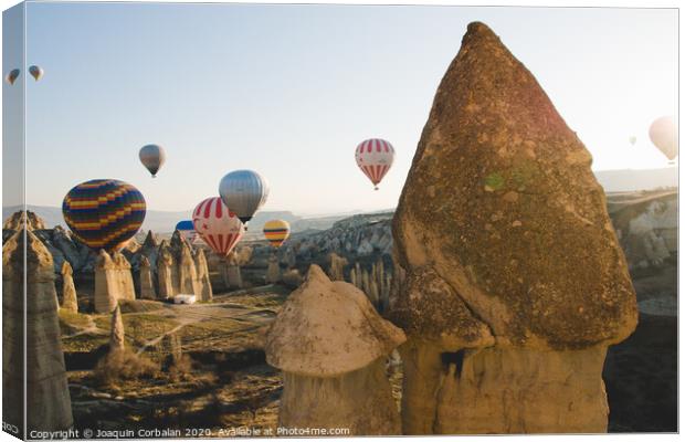 Goreme, Turkey - April 4, 2012: Hot air balloons for tourists flying over rock formations at sunrise in the valley of Cappadocia. Canvas Print by Joaquin Corbalan