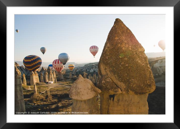 Goreme, Turkey - April 4, 2012: Hot air balloons for tourists flying over rock formations at sunrise in the valley of Cappadocia. Framed Mounted Print by Joaquin Corbalan