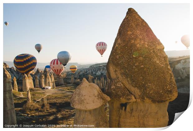 Goreme, Turkey - April 4, 2012: Hot air balloons for tourists flying over rock formations at sunrise in the valley of Cappadocia. Print by Joaquin Corbalan